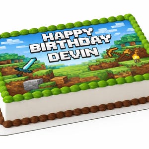 May include: Rectangular birthday cake with a Minecraft theme. The cake features a blue sky background with green grass and pixelated graphics. The words "HAPPY BIRTHDAY DEVIN" are displayed in white block letters. Green and brown frosting decorate the edges.