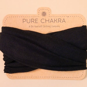 May include: A black fabric headband with the text "PURE CHAKRA A Be Yourself Clothing Company" on a brown paper tag.