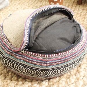 May include: A round, multi-colored, woven cushion with a zippered opening. The cushion is filled with a black fabric and has a mesh lining.
