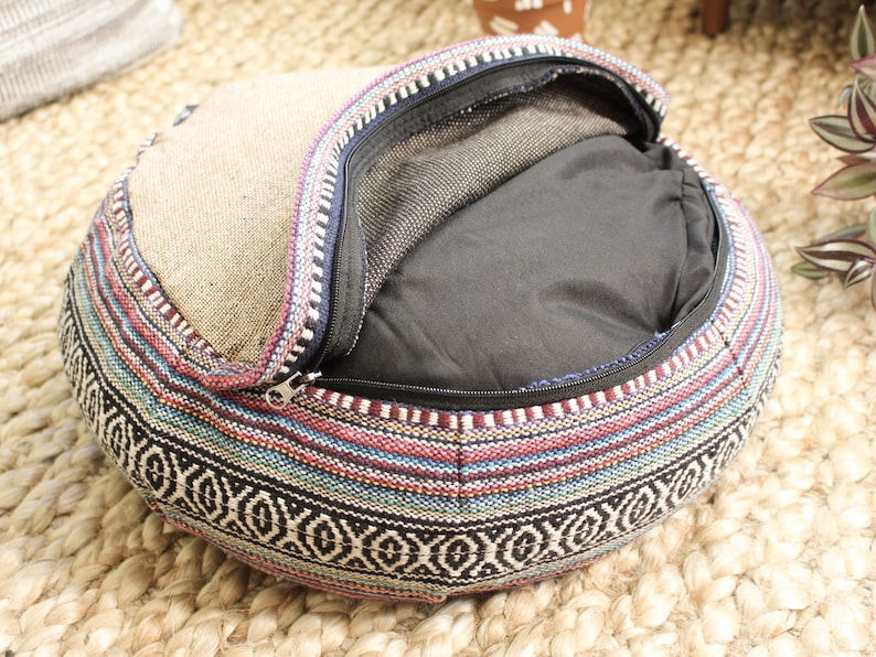 May include: A round, multi-colored, woven cushion with a zippered opening. The cushion is filled with a black fabric and has a mesh lining.