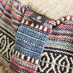 May include: Close-up of a colorful woven meditation cushion with a black label that reads "PURE CHAKRA".