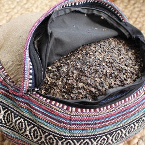 May include: A colorful, patterned meditation cushion filled with buckwheat hulls. The cushion is open, revealing the buckwheat hulls inside.