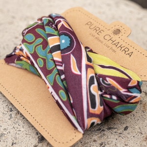 May include: A colorful patterned fabric scarf with a brown paper tag that reads "PURE CHAKRA Live Hippie. Live Free."