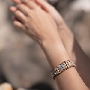 May include: A bracelet made of light blue and brown stone beads with a brown leather strap.