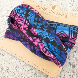 May include: A colorful headband with a geometric pattern in shades of blue, pink, and purple, displayed on a cardboard tag. The tag reads "PURE CHAKRA" with the tagline "Live Hippie. Live Free."