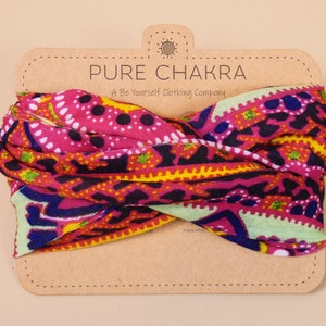May include: A pink, yellow, green, and blue patterned headband with the text "PURE CHAKRA A Be Yourself Clothing Company" on a brown card.