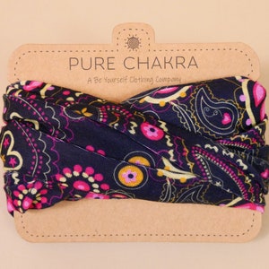 May include: A navy blue fabric headband with a paisley pattern in pink, yellow, and white. The headband is on a brown card with the text "PURE CHAKRA A Be Yourself Clothing Company".