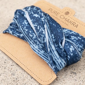 May include: A blue and white patterned fabric headband with the text "PURE CHAKRA Live Happy. Live Free." on a brown card.
