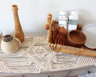 May include: A woven table runner with a geometric pattern, a wooden vase, two woven baskets, a wicker basket with wooden bowls, a pineapple-shaped wooden carving, and two white plates.