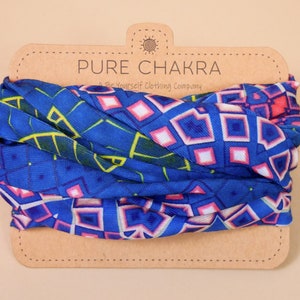 May include: A blue and pink patterned fabric tube scarf with a brown paper tag that reads "PURE CHAKRA A Be Yourself Clothing Company".