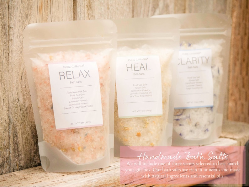 May include: Three clear plastic pouches filled with bath salts. The pouches are labeled "Relax", "Heal", and "Clarity". The bath salts are a mix of pink, white, and blue crystals. The pouches are sitting on a wooden surface. Handmade Bath Salts. We will include one of three scents selected to best match your gift box. Our bath salts are rich in minerals and made with natural ingredients and essential oils.