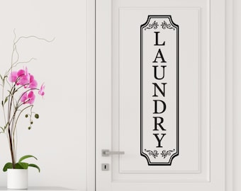 Peut inclure: Autocollant en vinyle noir et blanc avec le mot "LAUNDRY" écrit verticalement dans une police décorative. L'autocollant est fixé à une porte blanche.