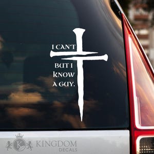 May include: White decal featuring a cross made of a nail and a hammer. The text "I CAN'T BUT I KNOW A GUY" is displayed in white. The decal is on the rear window of a vehicle.