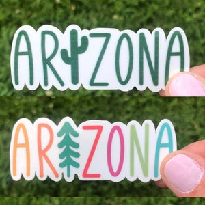 May include: Four stickers with the word "ARIZONA" in different colors and fonts. Each sticker features a different green plant design, including a cactus and a pine tree.