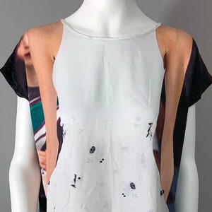 May include: A white dress with a floral pattern and a white bodice. The dress is made of a sheer fabric and has a loose fit. The dress is being displayed on a mannequin.