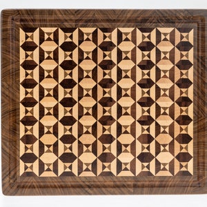 May include: A rectangular wooden cutting board with a geometric pattern of light and dark wood. The board has a dark wood border.