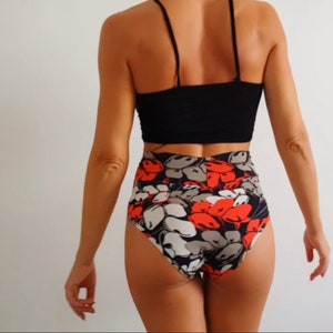 Può includere: Top corto nero con spalline sottili abbinato a un fondo a vita alta. Il fondo presenta un motivo floreale con fiori rossi, grigi e bianchi su sfondo scuro. Un completo alla moda.