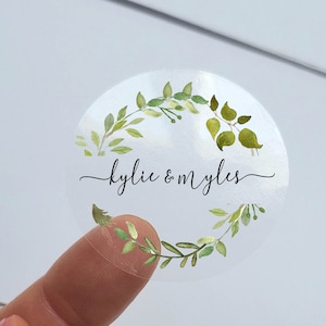 May include: Clear round sticker with a green watercolour wreath and the text "kylie & myles" in black script.