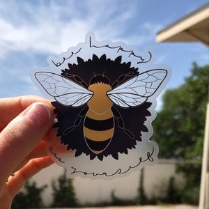 May include: A clear sticker with a bee illustration and the text "be happy be yourself".
