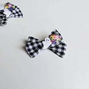 May include: Black and white checkered fabric bow with a white ghost and colorful sequins.