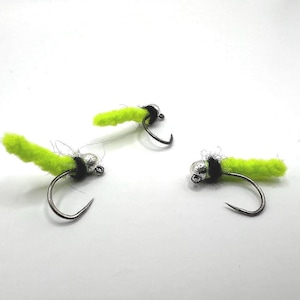 May include: Three fly fishing lures with bright green bodies and silver beads. The lures are tied with black thread.