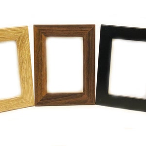 May include: Three picture frames in different colors: natural wood, dark wood, and black. The frames are all the same size and shape, and they are all empty.