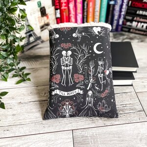 May include: Black book cover with a white design of skeletons, roses, and other gothic imagery. The text "Till Death" is featured on the cover.