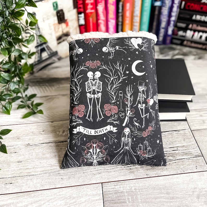 May include: Black book cover with a white design of skeletons, roses, and other gothic imagery. The text "Till Death" is featured on the cover.