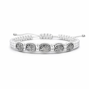 May include: White macram&eacute; bracelet with five silver-toned, circular charms. The charms are evenly spaced along the bracelet's centre. The bracelet has an adjustable sliding knot closure. The design is simple and elegant.