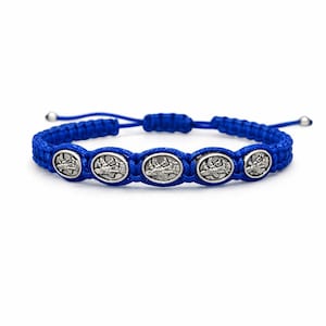 May include: A blue braided bracelet with five silver oval charms. Each charm has a detailed design. The bracelet has adjustable ends with silver beads. The background is plain white.