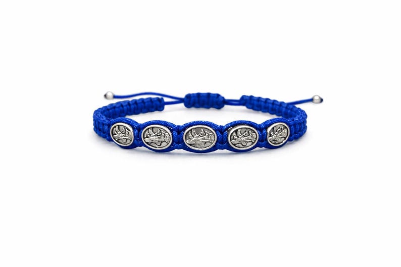 May include: A blue braided bracelet with five silver oval charms. Each charm has a detailed design. The bracelet has adjustable ends with silver beads. The background is plain white.