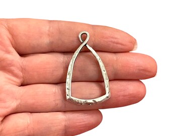 Puede incluir: Pendiente de plata con forma de lágrima y textura martillada. El pendiente tiene un bucle en la parte superior para sujetar una cadena.