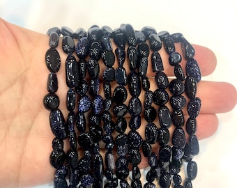 May include: A strand of dark blue gemstone beads with a speckled, glittery finish. The beads are smooth and oval-shaped, and they are strung together on a clear thread.
