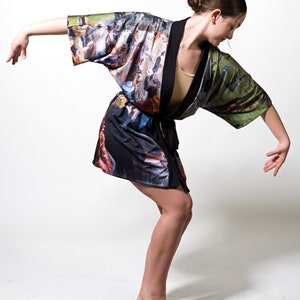 May include: A kimono-style robe with a colorful, impressionistic print. The robe features a black trim and a tie closure. The fabric design includes a variety of colors, including blues, greens, and browns, creating a unique artistic look.