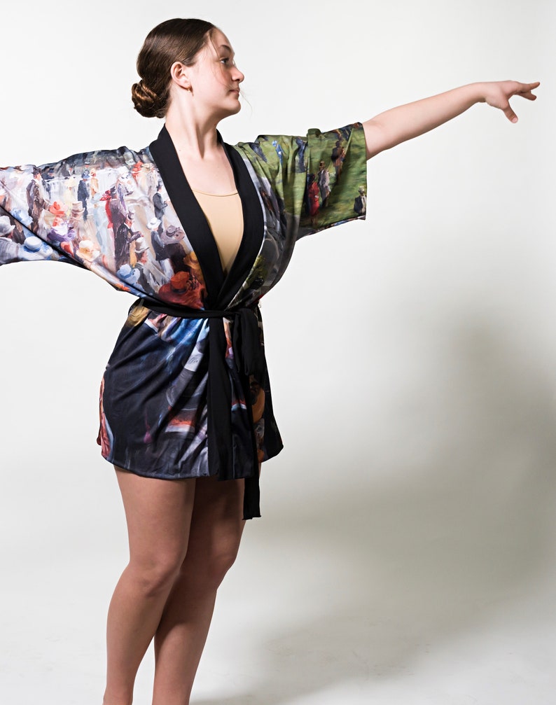 May include: A colorful kimono-style robe with a black trim and belt. The robe features a vibrant print of an Impressionist painting, with figures and landscapes. The sleeves are wide, and the robe is knee-length.