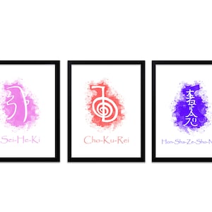 Op de afbeelding: Drie ingelijste kunstprints met Reiki-symbolen. Elke print heeft een zwarte lijst en een witte achtergrond. De symbolen zijn in roze, rood en blauw, met de bijbehorende tekst: Sei-He-Ki, Cho-Ku-Rei en Hon-Sha-Ze-Sho-Nen.
