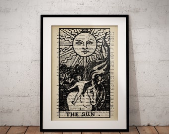 May include: Black and white illustration of The Sun tarot card. The card features a sun with a face, a man riding a white horse, and a tower in the background. The text "THE SUN" is printed at the bottom of the card.