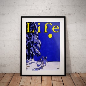 May include: Framed vintage "Life" magazine cover art. The artwork features a winter scene with a snowy tree, a figure pulling a sled, and the word "Life" in yellow against a blue background. The artwork is framed in a black frame.