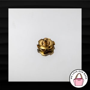 May include: Gold-toned metal bag closure with a star-shaped design. The closure has a small, round knob on top.