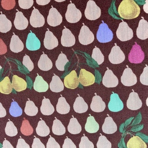 May include: A brown fabric with a repeating pattern of white pears. Some of the pears are highlighted in different colors, including green, blue, pink, and yellow.
