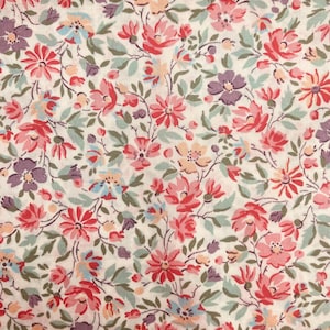 Puede incluir: Primer plano de una tela floral con un patrón repetido de flores rojas, rosas, moradas y melocotón. Las flores están sobre un fondo crema, con hojas verdes y finos tallos marrones. La tela tiene una estética vintage y cottagecore.