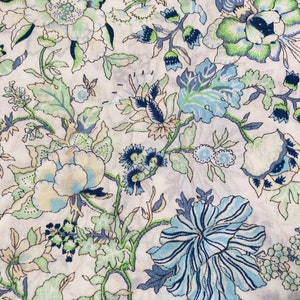 Puede incluir: Una tela blanca con un patrón floral azul y verde. Las flores son estilizadas y tienen un aspecto vintage.