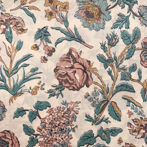 May include: A white fabric with a floral pattern. The flowers are in shades of pink, blue, and green. The fabric has a vintage feel.