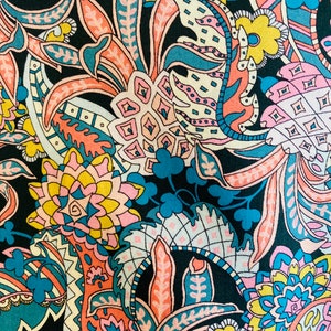 Puede incluir: Una tela de estampado paisley colorido sobre fondo negro. El estampado presenta diseños florales de color rosa, amarillo, azul y blanco.