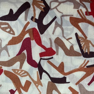 May include: A white fabric with a repeating pattern of brown, red, and black high-heeled shoes. The shoes are stylized and abstract.