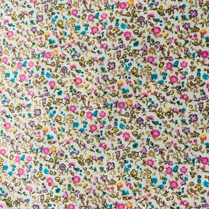 May include: A white fabric with a small-scale floral print. The print features pink, blue, and yellow flowers on a white background.