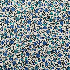 May include: A white fabric with a repeating pattern of blue and teal flowers and leaves.