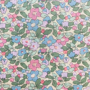 May include: A floral fabric with a repeating pattern of pink, blue, and purple flowers, green leaves, and small red berries on a cream background. The design is delicate and detailed, suitable for various craft projects.