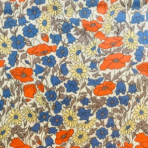 Könnte beinhalten: Ein weißer Stoff mit einem sich wiederholenden Muster aus roten, gelben und blauen Blumen. Die Blumen sind stilisiert und haben einen Vintage-Look.