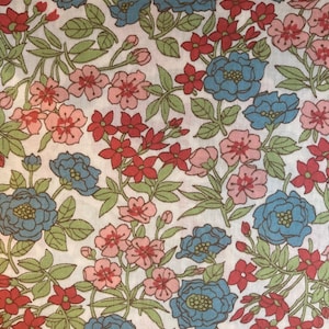 Puede incluir: Una tela blanca con un patrón floral con flores azules, rosas y rojas. Las flores están dispuestas en un patrón repetitivo sobre un fondo blanco.